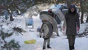 Two families grill kebabs in winter in a snowy pine forest.