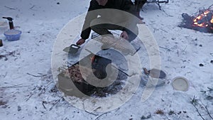 Two families grill kebabs in winter in a snowy pine forest.