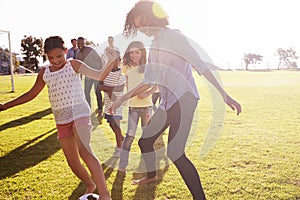 Two families in a park playing football