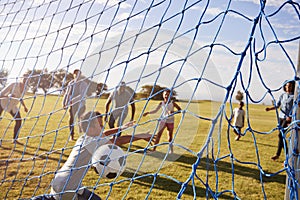 Two families playing football in park, scoring a goal