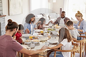 Two Families Praying Before Enjoying Meal At Home Together photo