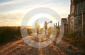 Two farmers carrying a basket of fresh produce and walking against a sunset background. Unrecognisable woman celebrating