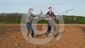 Two farmers dance energetically with seedlings in their hands, imitating rock musicians