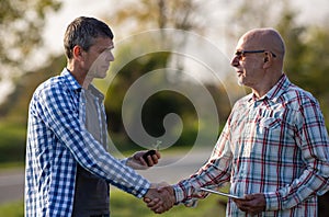 Two farmers shaking hands in field