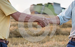 Two farmers shaking hands in field