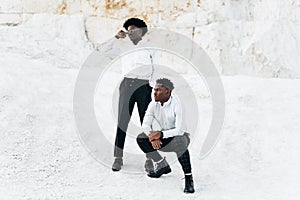 Two fashionable elegant black africans posing in full growth outdoors near mountains and rocks