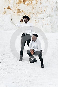 Two fashionable elegant black africans posing in full growth outdoors near mountains and rocks