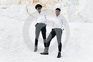 Two fashionable elegant black africans posing in full growth outdoors near mountains and rocks