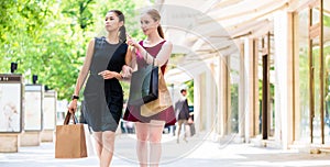 Two fashionable young women walking in the city during shopping