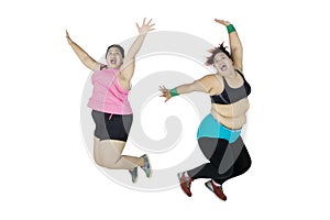 Two fat women jumping together on studio