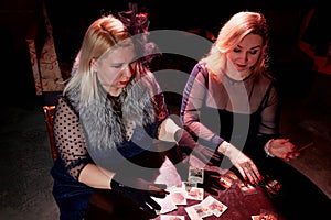 Two fat women with playing cards in a dark room with red light. Gangsters style
