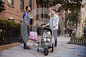 Two father friends with two kids talking in the street