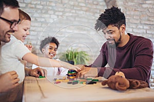 Two fathers play educational games with their children