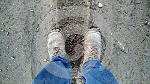 Two feet standing on a muddy, wet path, car track