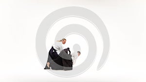 Two fellows in kimono performing aikido using bokken. Isolated, white.