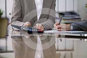 Two female accountants checking financial statement or counting by calculator income for tax form, hands close-up