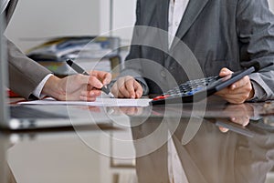 Two female accountants checking financial statement or counting by calculator income for tax form, hands close-up