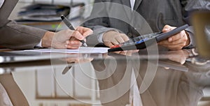 Two female accountants checking financial statement or counting by calculator income for tax form, hands close-up