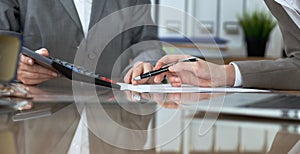 Two female accountants checking financial statement or counting by calculator income for tax form, hands close-up