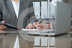 Two female accountants checking financial statement or counting by calculator income for tax form, hands close-up