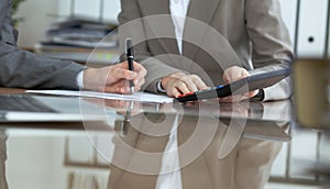 Two female accountants checking financial statement or counting by calculator income for tax form, hands close-up