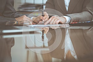 Two female accountants checking financial statement or counting by calculator income for tax form, hands close-up