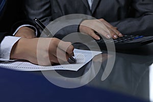 Two female accountants checking financial statement or counting by calculator income for tax form, hands close-up