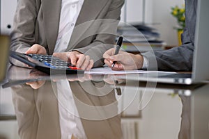 Two female accountants checking financial statement or counting by calculator income for tax form, hands close-up