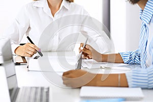 Two female accountants checking financial statement or counting by calculator income for tax form, hands at meeting