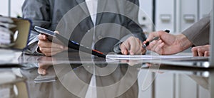 Two female accountants counting on calculator income for tax form completion, hands closeup. Internal Revenue Service