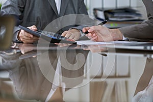 Two female accountants counting on calculator income for tax form completion, hands closeup. Internal Revenue Service