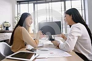 Two female accountants have a team meeting to summarize financial information in the office