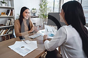 Two female accountants have a team meeting to summarize financial information in the office