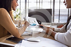 Two female accountants have a team meeting to summarize financial information in the office