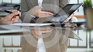 Two female accountants using tablet while checking financial statement or counting income for tax form, hands close-up