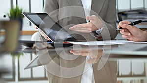 Two female accountants using tablet while checking financial statement or counting income for tax form, hands close-up