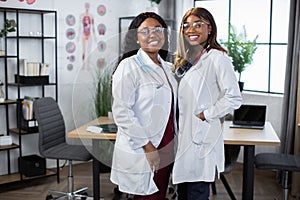 Two female African American doctors or nurses colleagues, smiling to camera