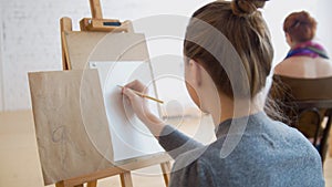 Two female artists sketching model in bright drawing class