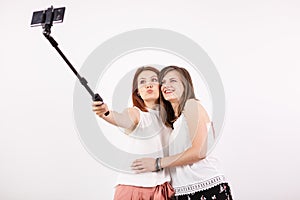 Two female best friends having a lot of fun while taking a selfie with a selfie stick