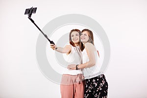 Two female best friends having a lot of fun while taking a selfie with a selfie stick
