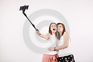 Two female best friends having a lot of fun while taking a selfie with a selfie stick