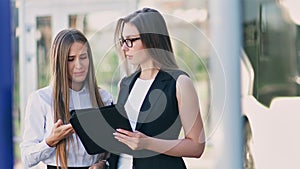 Two female businesswoman having informal team meeting standing outdoor near office