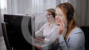 Two female call center operators with headset work in a support service office.