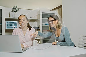 Two female colleagues discuss a project with laptop in the office