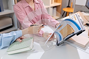 Two female colleagues discussing business reports together in a modern office environment, representing teamwork, data analysis,