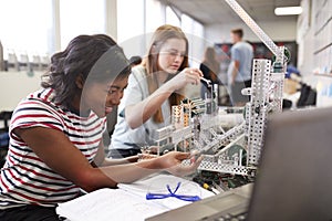 Two Female College Students Building Machine In Science Robotics Or Engineering Class