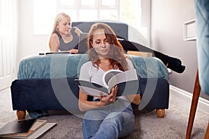 Two Female College Students In Shared House Bedroom Studying Together