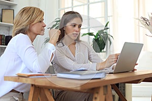 Two female collegues working with laptop and discussing new project