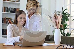 Two female collegues working with laptop and discussing new project