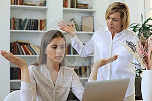 Two female collegues working with laptop and discussing new project photo